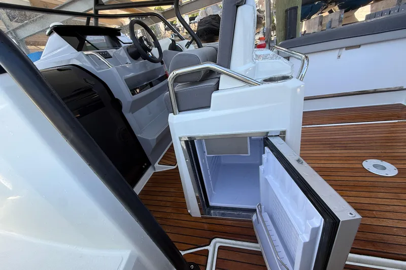 Slide: The Image of 2020 Jeanneau Leader 7.5 CC boat interior with open fridge and wooden deck. - 24