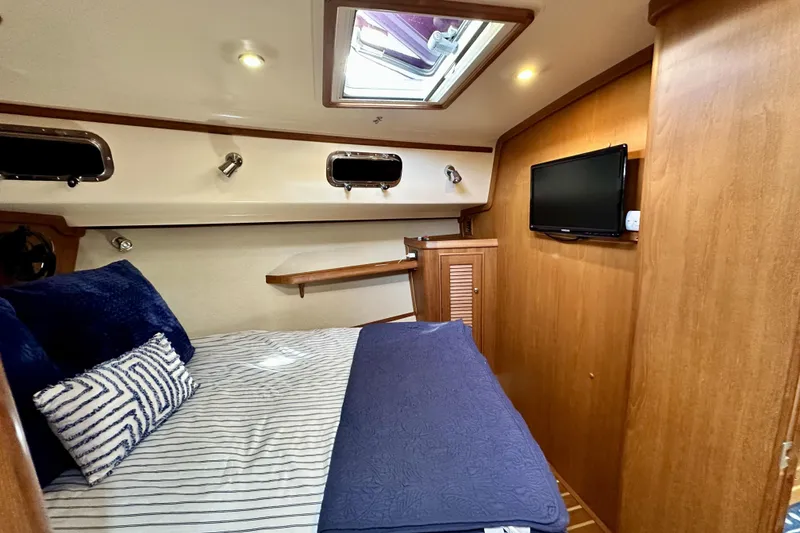 Slide: The Image of Cozy cabin interior of 2006 Island Packet 440 yacht with bed, TV, and wooden accents. - 51