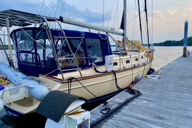 Slide: The Image of 2006 Island Packet 440 sailboat docked at a marina, featuring a blue canopy and calm waters. - 10