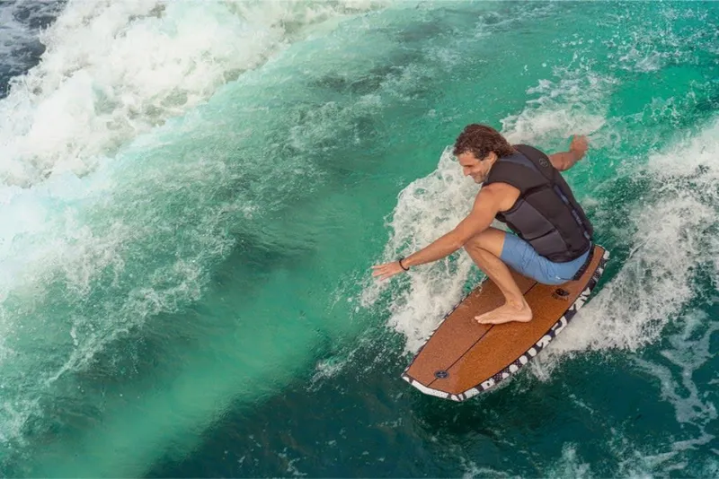 Slide: The Image of A man surfs on a wave behind a boat. - 9