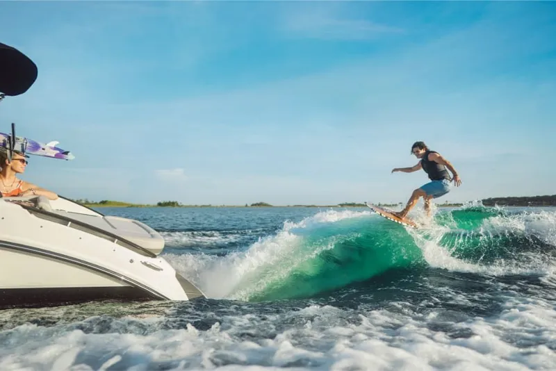 Slide: The Image of A surfer rides a wave behind a Sea Ray SLX 260 Surf boat on a sunny lake. - 16