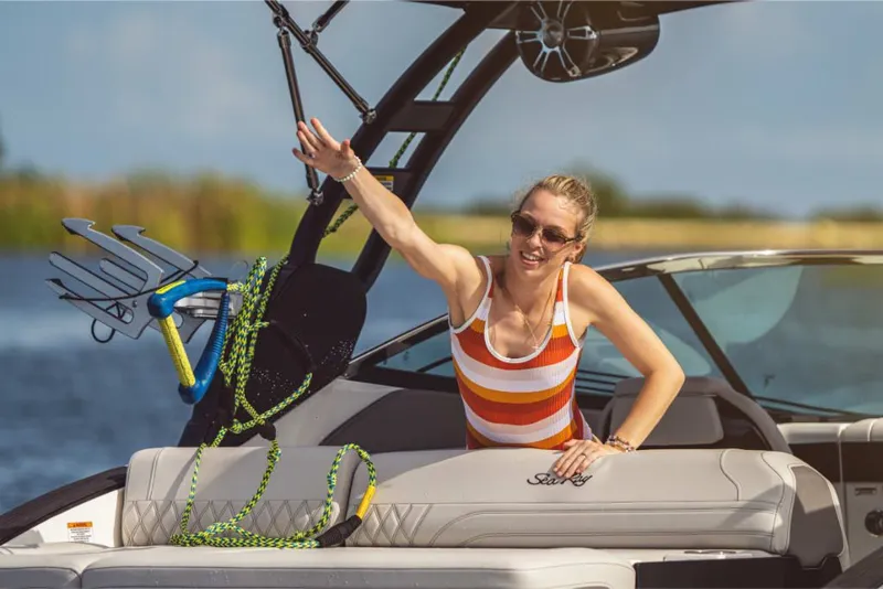 Slide: The Image of A woman in a striped swimsuit waves on a Sea Ray SLX 260 Surf boat. - 22