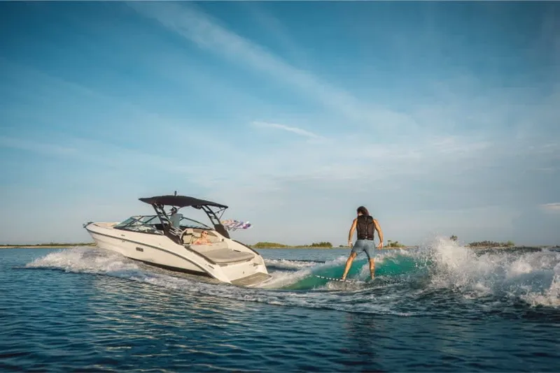 Slide: The Image of A 2026 Sea Ray SLX 260 Surf towing a surfer on calm waters. - 4