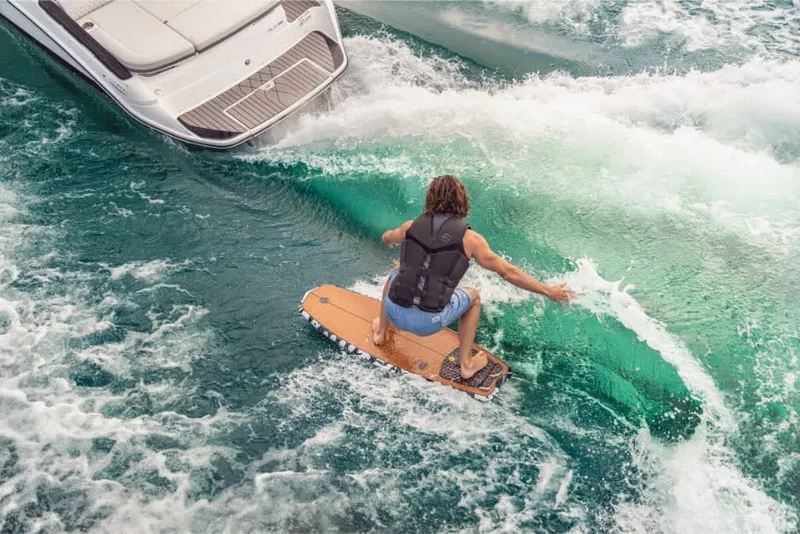 Slide: The Image of A surfer rides a wave next to a Sea Ray SLX 260 Surf boat. - 19