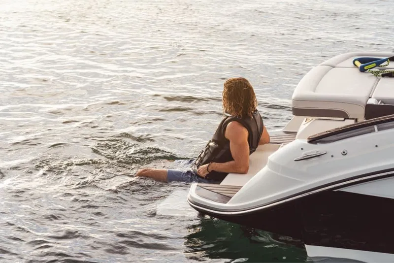 Slide: The Image of A man sits on the stern of a 2026 Sea Ray SLX 260 Surf, enjoying the water. - 6