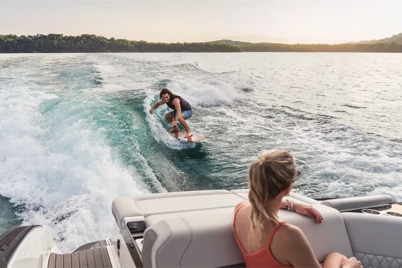 Slide: The Image of A person surfs behind a Sea Ray SLX 260 Surf boat while another watches. - 7