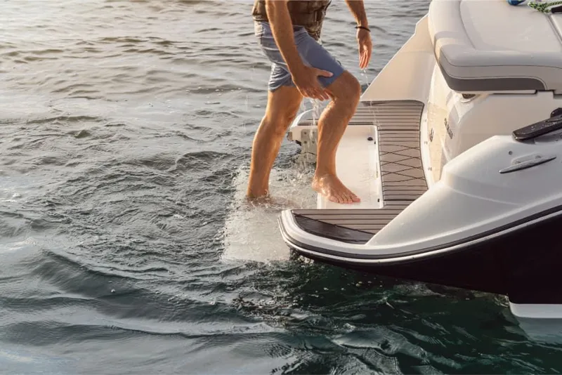 Slide: The Image of A person steps off a Sea Ray SLX 260 Surf boat into the water. The boat has a rear platform. - 5