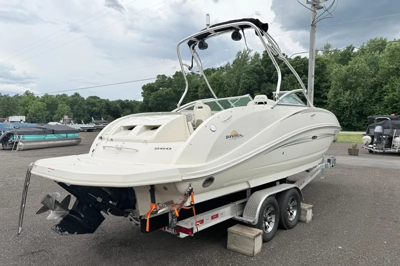 Slide: The Image of 2007 Sea Ray 260 Sundeck boat on trailer, parked outdoors with trees in background. - 11