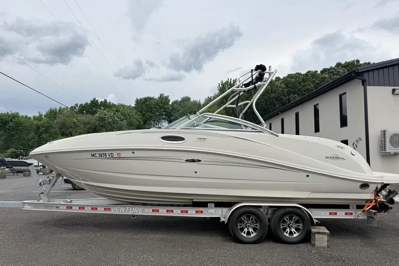 The Image of 2007 Sea Ray 260 Sundeck boat on trailer, parked outdoors near building. - 1