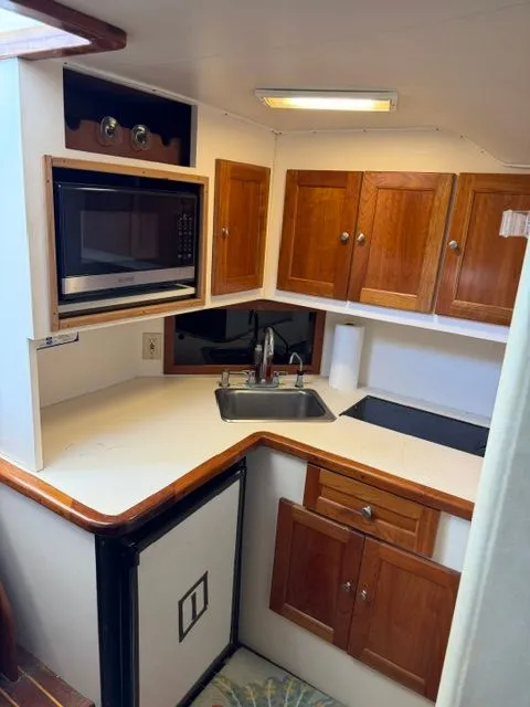 Slide: The Image of Compact boat kitchen with wooden cabinets, sink, microwave, and stove. - 8