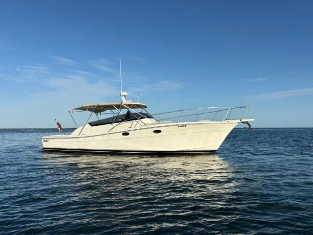 The Image of A cream-colored boat with a canopy cruises on calm water under a blue sky. - 0