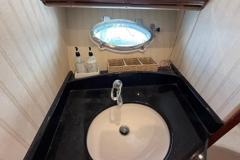 Slide: The Image of Bathroom sink area on 2005 Ocean Alexander 48 Altus yacht, featuring a round basin and porthole window. - 57