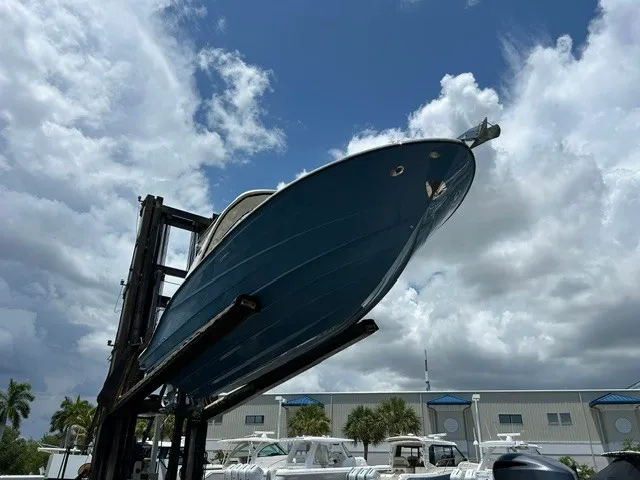 Slide: The Image of A 2021 Sea Ray SLX 310 Outboard is lifted by a forklift, set against a cloudy sky. - 33