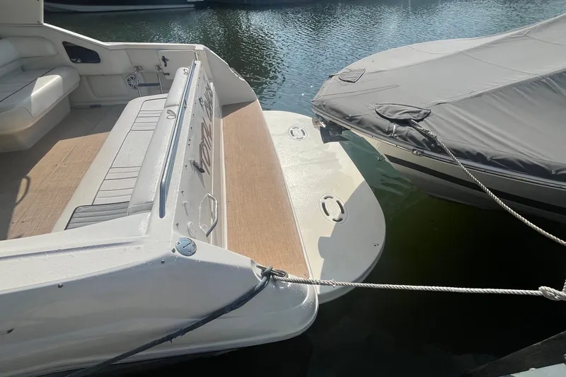 Slide: The Image of 1994 Sea Ray 330 Express Cruiser docked, showing swim platform and covered seating area. - 5
