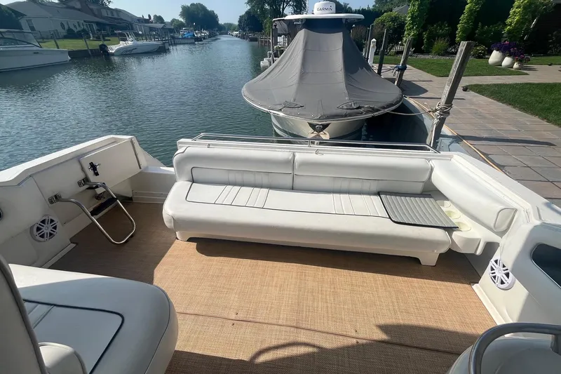 Slide: The Image of 1994 Sea Ray 330 Express Cruiser interior with white seating, docked by a canal. - 6