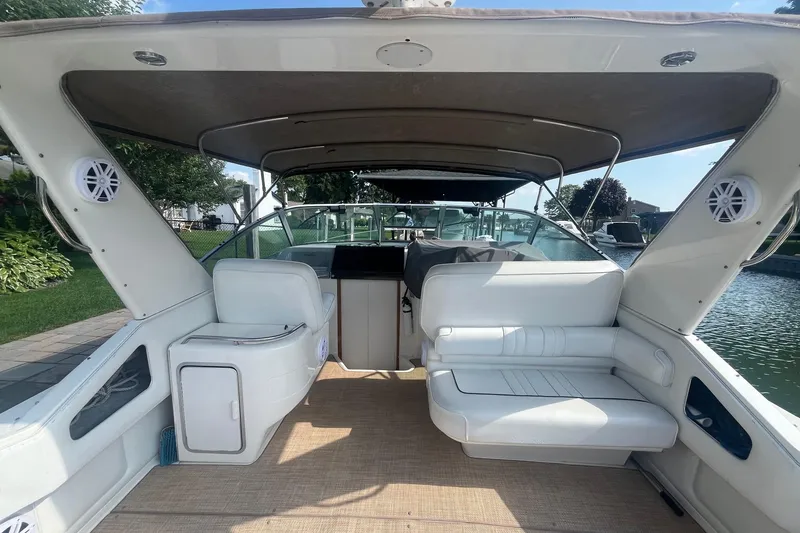 Slide: The Image of 1994 Sea Ray 330 Express Cruiser interior with white seating and canopy, docked by water. - 8