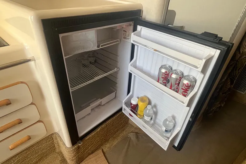 Slide: The Image of Mini fridge inside 1994 Sea Ray 330 Express Cruiser, stocked with drinks and condiments. - 29