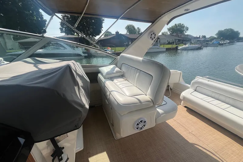 Slide: The Image of 1994 Sea Ray 330 Express Cruiser interior with white seating, docked by a serene waterfront. - 12