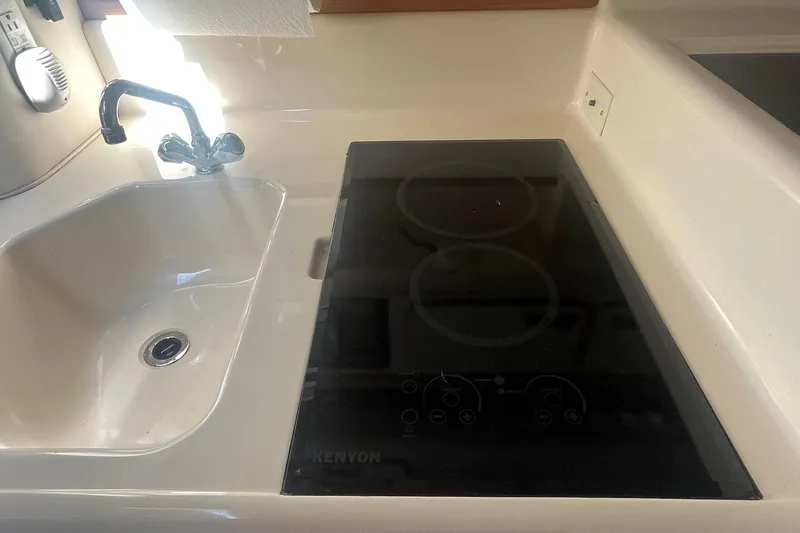 Slide: The Image of 1994 Sea Ray 330 Express Cruiser kitchen with sink and Kenyon electric cooktop. - 27