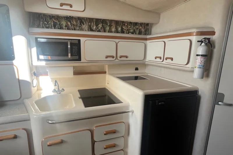 Slide: The Image of 1994 Sea Ray 330 Express Cruiser kitchen with microwave, sink, stove, and cabinets. - 23