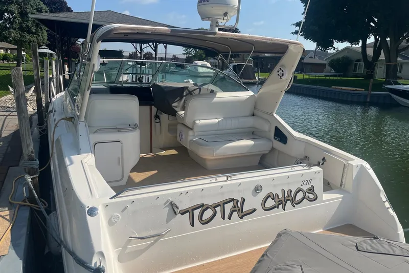 Slide: The Image of 1994 Sea Ray 330 Express Cruiser docked, featuring spacious seating and "Total Chaos" name. - 4