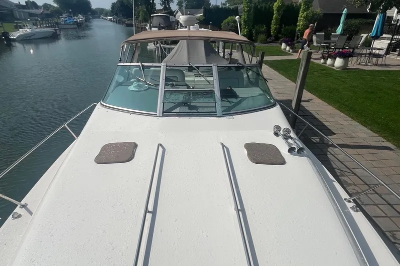 Slide: The Image of 1994 Sea Ray 330 Express Cruiser docked by a canal, featuring spacious deck and windshield. - 2