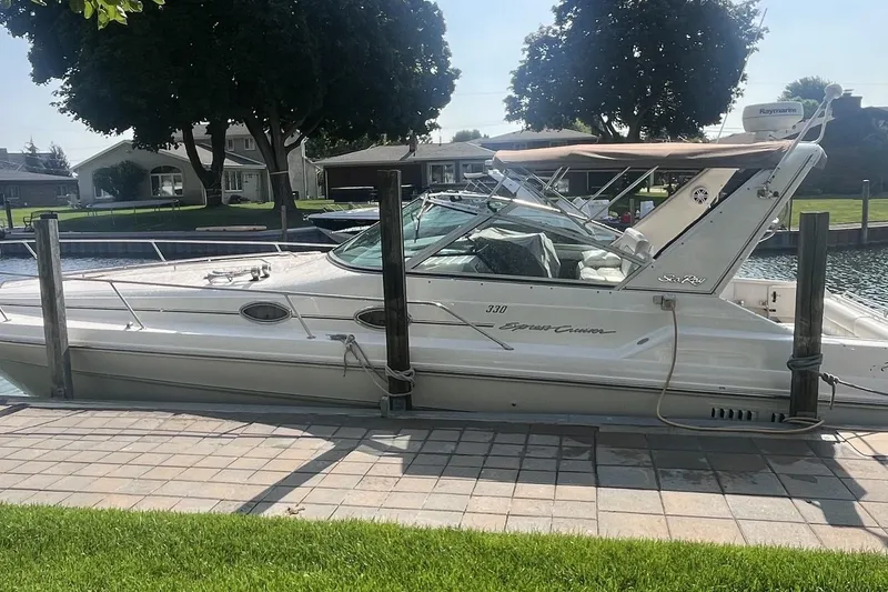 The Image of 1994 Sea Ray 330 Express Cruiser docked by a waterfront home. - 0