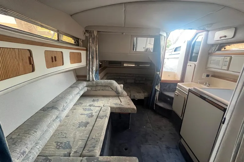 Slide: The Image of Interior of a 1993 Sea Ray Sundancer 330, featuring cozy seating and compact kitchen area. - 12
