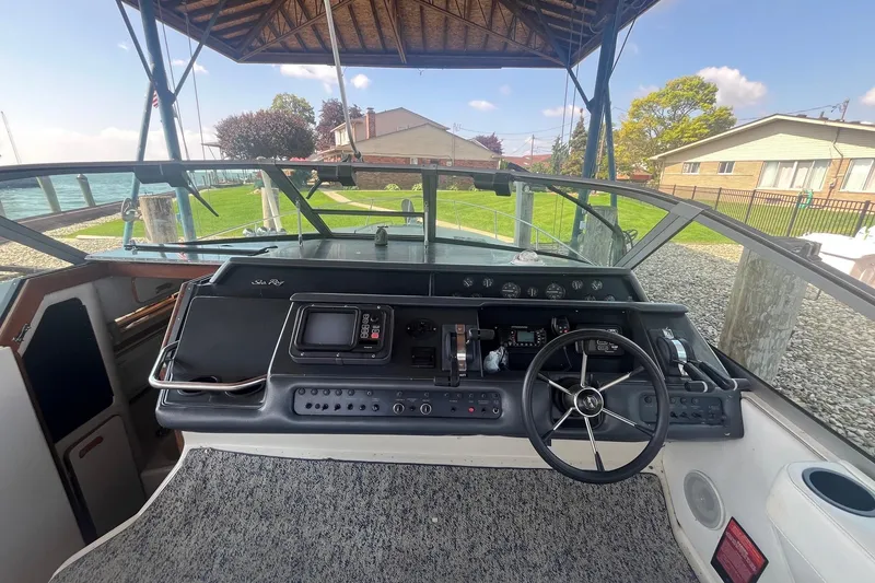 Slide: The Image of 1993 Sea Ray Sundancer 330 helm with steering wheel and control panel, docked under a canopy. - 8
