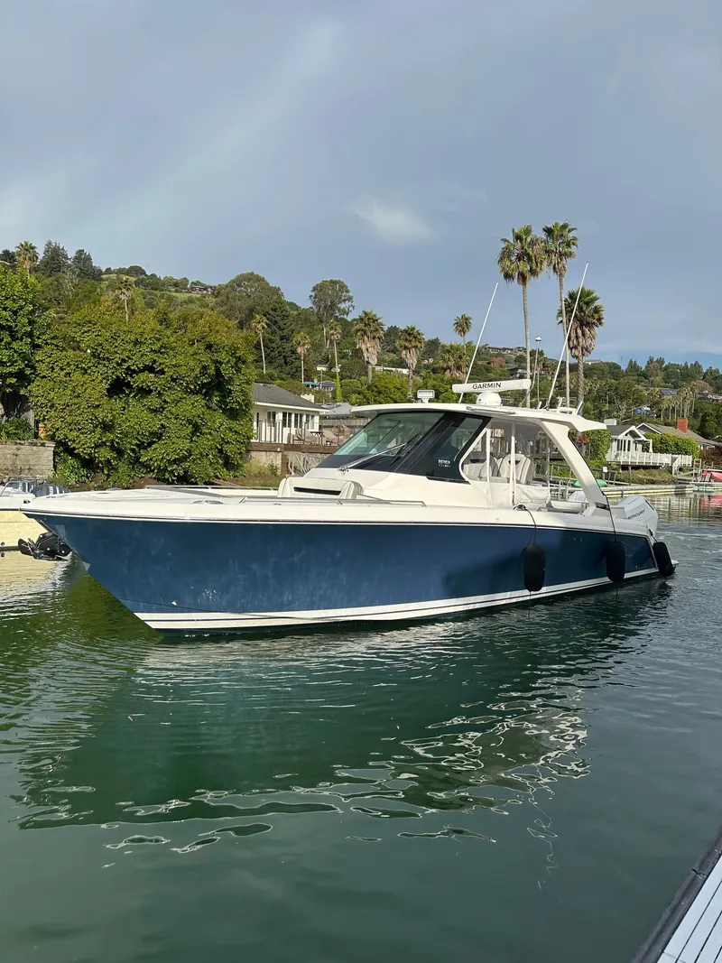 Slide: The Image of A sleek blue and white boat anchored calmly on tranquil waters. - 12
