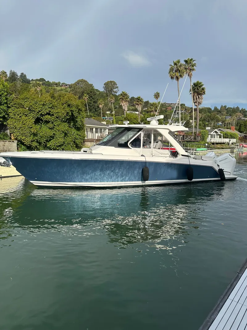 Slide: The Image of A sleek 2024 Tiara Yachts 34 LS is on the water, surrounded by lush greenery. - 6
