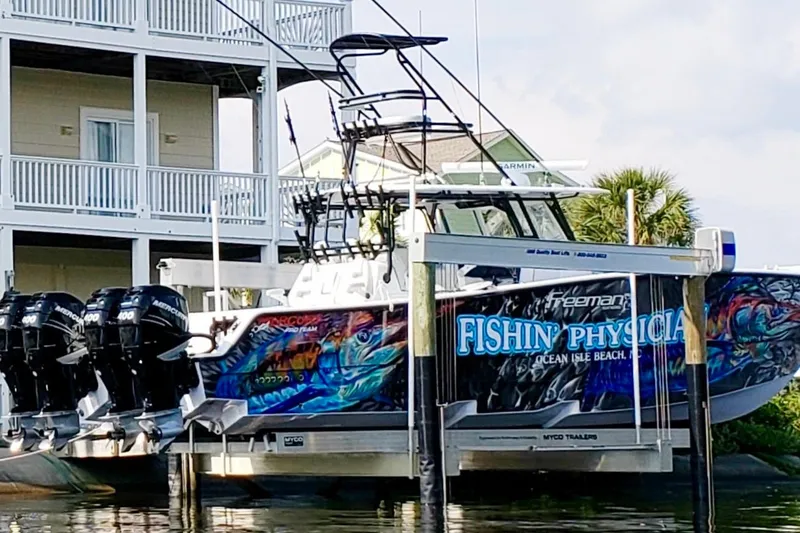 Slide: The Image of Freeman 42LR 2020 boat with vibrant graphics docked near a waterfront house. - 6
