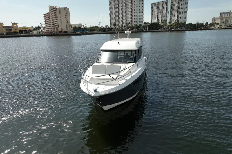 Slide: The Image of 2022 Regal 42 XO yacht on calm water with city skyline backdrop. - 16