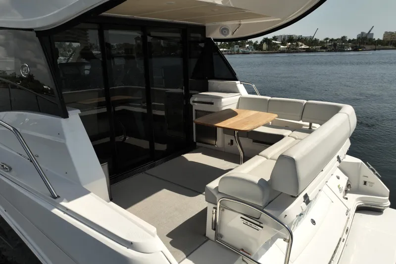 Slide: The Image of 2022 Regal 42 XO yacht with spacious outdoor seating and table, docked by the water. - 6