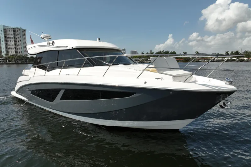 Slide: The Image of 2022 Regal 42 XO yacht cruising on a sunny day, with cityscape background. - 9