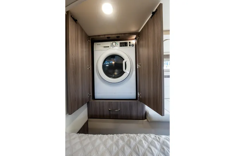 Slide: The Image of Laundry area with washer in 2022 Regal 42 XO yacht, featuring wooden cabinetry. - 61