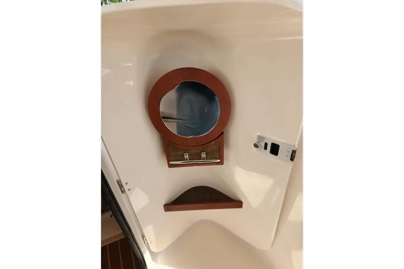 Slide: The Image of Interior view of a 2015 Grady-White Freedom 307 boat with a round mirror and shelf. - 17