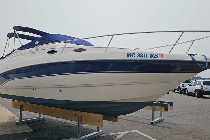 Slide: The Image of 1999 Chaparral Signature 240 boat with blue cover on a trailer in a parking lot. - 1