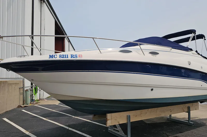 The Image of 1999 Chaparral Signature 240 boat on a trailer, parked near a building. - 0