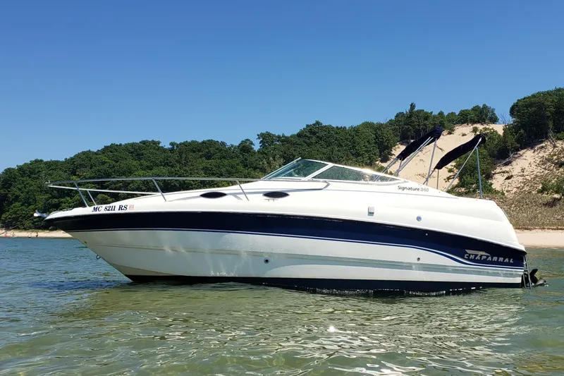 The Image of 1999 Chaparral Signature 240 boat on clear water near a sandy beach and lush greenery. - 3