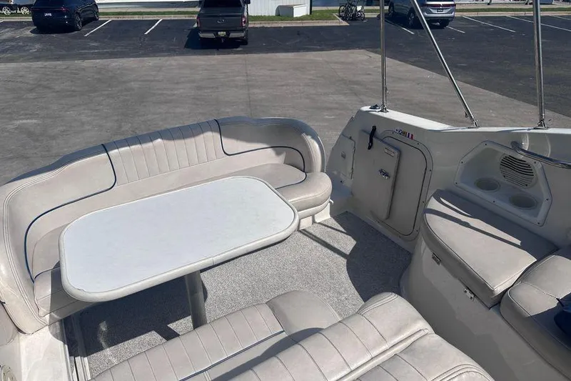 Slide: The Image of 1999 Chaparral Signature 240 boat interior with seating and table in a parking lot. - 9