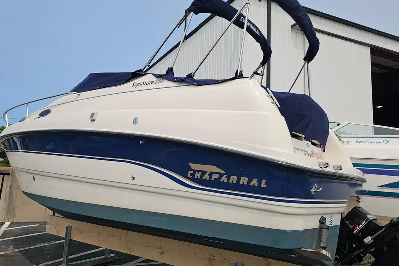 Slide: The Image of 1999 Chaparral Signature 240 boat with blue and white design, docked near a warehouse. - 2