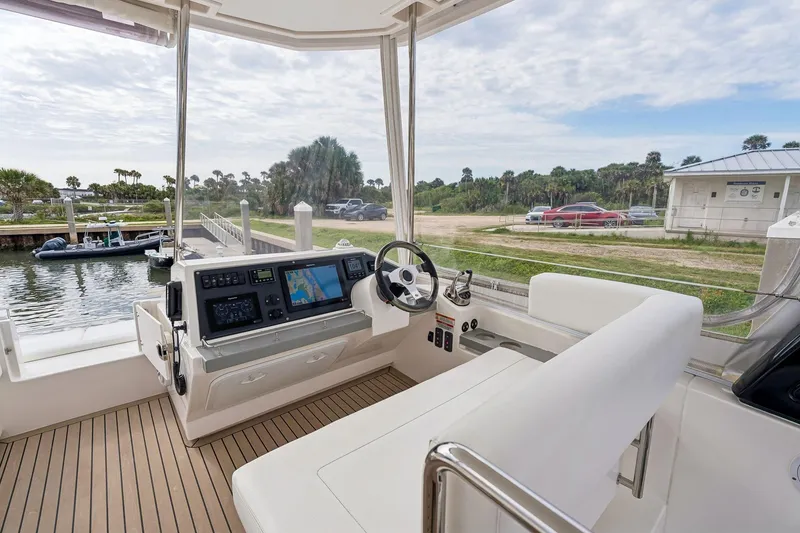 Slide: The Image of 2021 Leopard 43 Powercat helm with navigation screens, docked near lush greenery. - 13