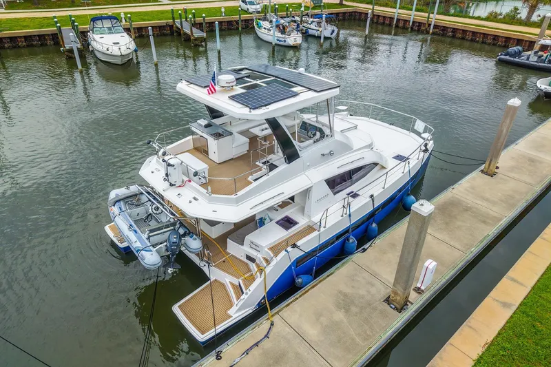 Slide: The Image of 2021 Leopard 43 Powercat docked in a marina, featuring solar panels and a dinghy. - 44