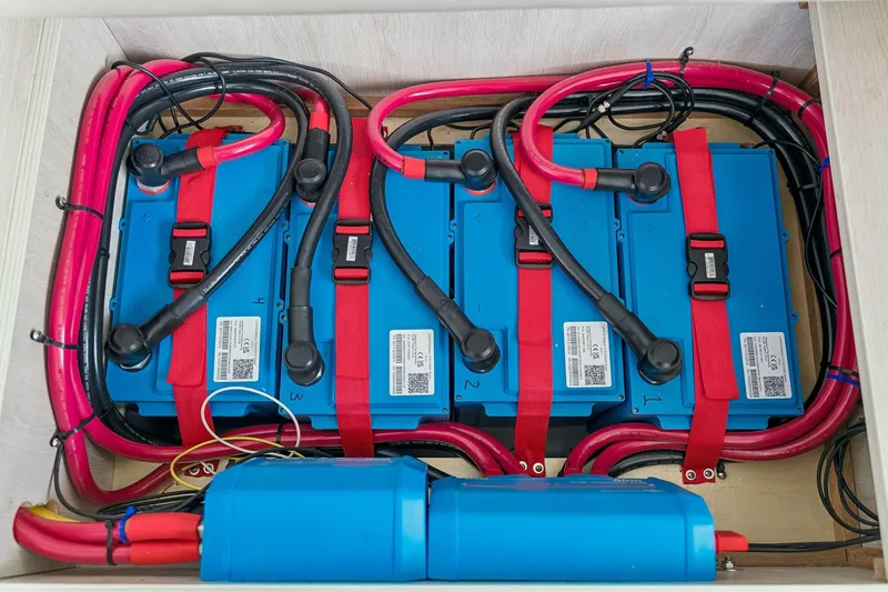 Slide: The Image of Battery compartment of a 2021 Leopard 43 Powercat with secured blue batteries and red cables. - 57
