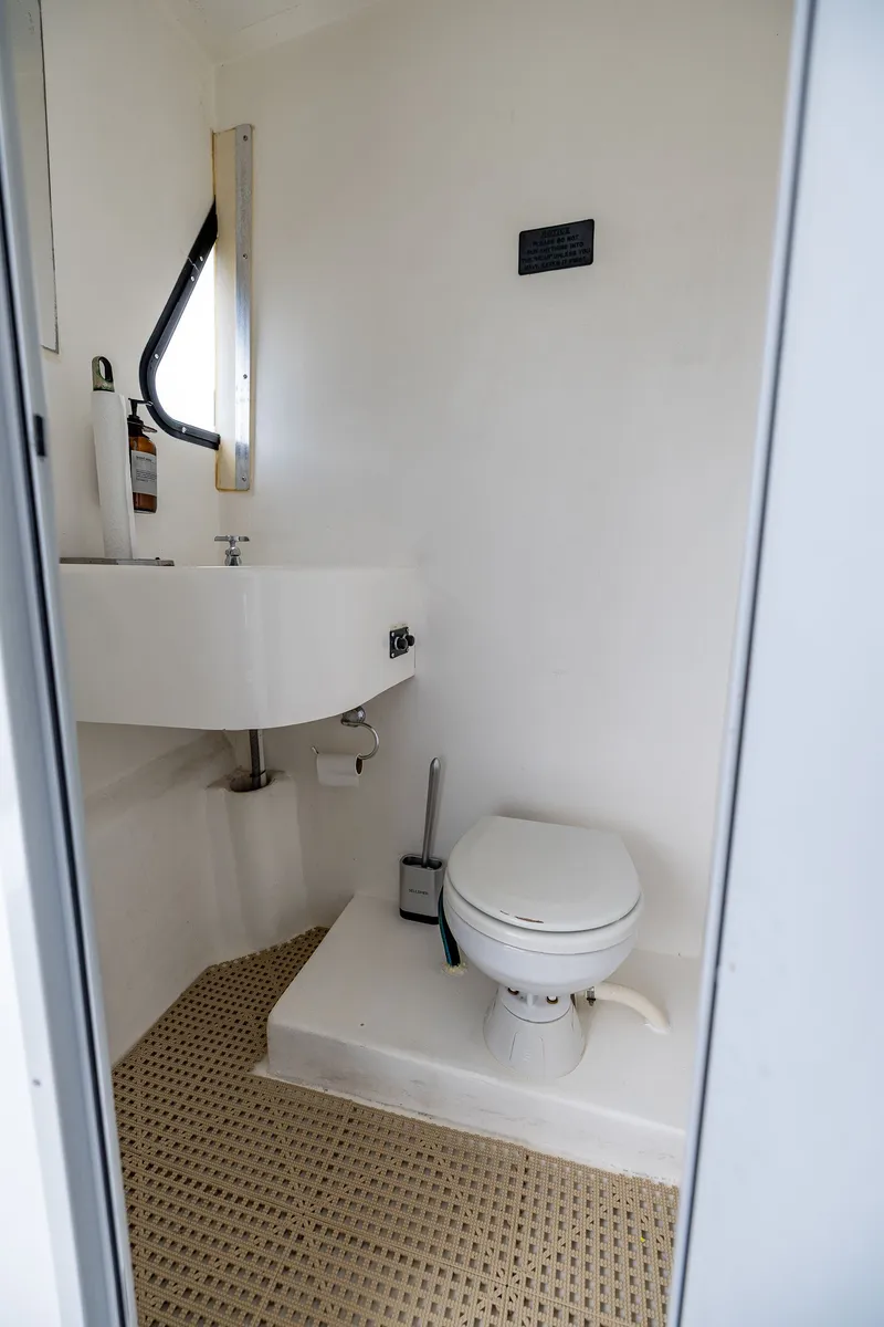 Slide: The Image of The image shows a simple boat bathroom with a toilet and sink. - 41
