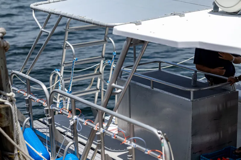 Slide: The Image of A dive boat with metal railings and blue life vests, docked at a pier. - 22