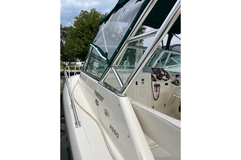 Slide: The Image of 2000 Pursuit 2860 Denali boat with green canopy, docked near trees. - 9