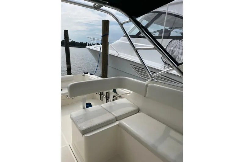 Slide: The Image of 2000 Pursuit 2860 Denali boat interior with white seating and docked view. - 14