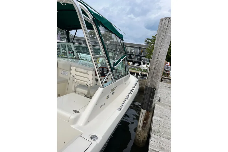 Slide: The Image of 2000 Pursuit 2860 Denali boat docked at a marina with green canopy. - 10